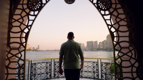 man on a balcony overlooking the nile river at sunset in cairo, egypt - drone flying forward
