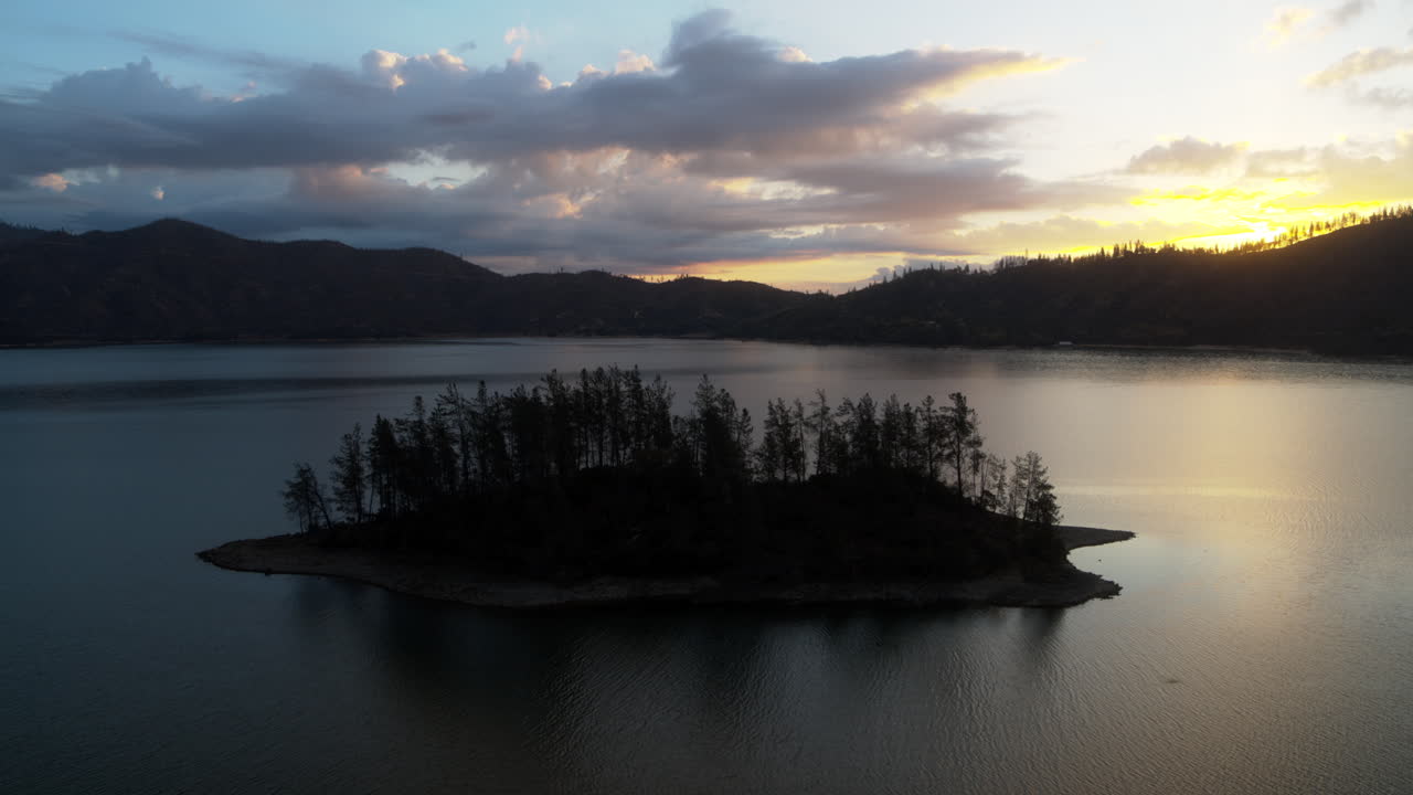 una muñeca aérea lenta sobre una isla con silueta en el lago whiskeytown durante el amanecer en el norte de california