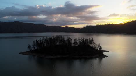 slow aerial dolly over a silhouetted island on whiskeytown lake during the sunrise in northern california