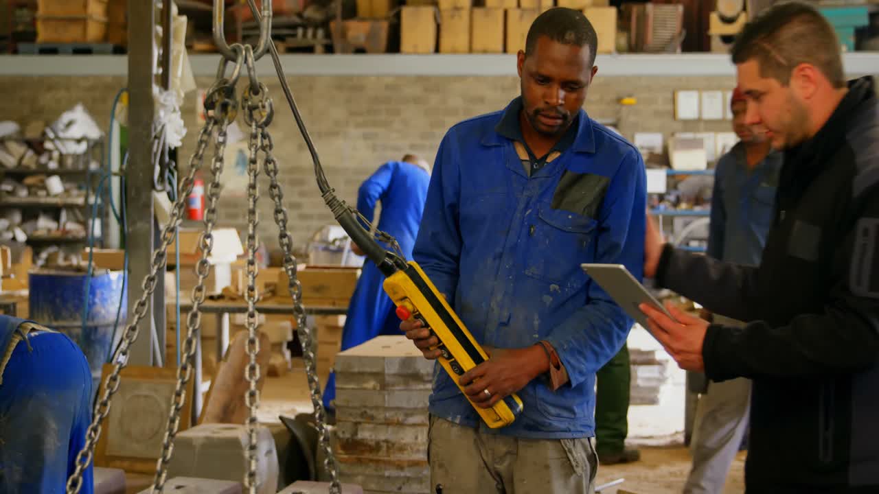 Workers maintaining record on digital tablet in foundry workshop 4k