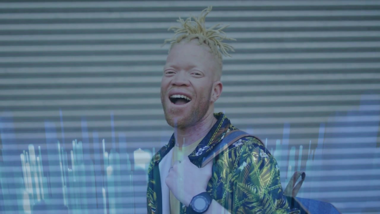 Vertical video: Smiling man in leaf shirt tugging blue pack while camera rolling at shutter, glitch