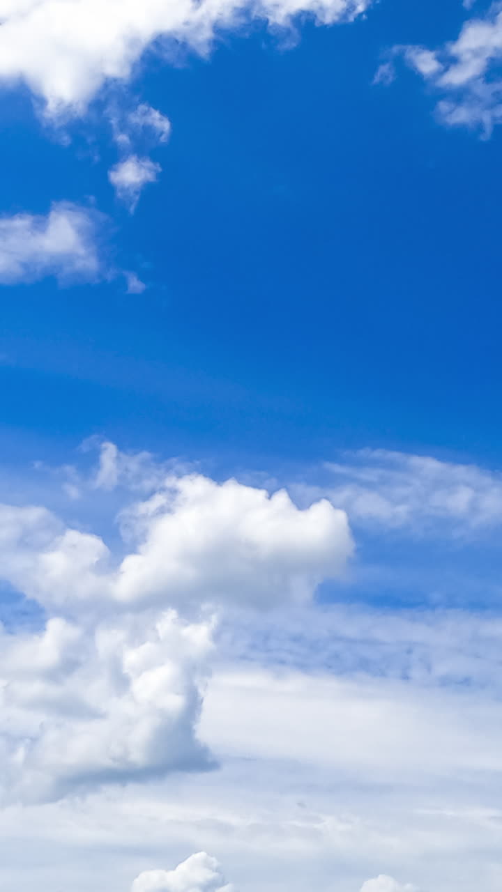 Heavenly beautiful blue skies with white clouds floating by. Cumulus and spindrift clouds transforming in the atmosphere. Timelapse. Vertical video