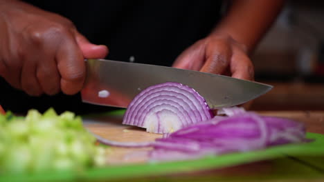 cortando fina y cuidadosamente una cebolla roja jugosa para una receta de ensalada fresca y saludable - cámara lenta aislada