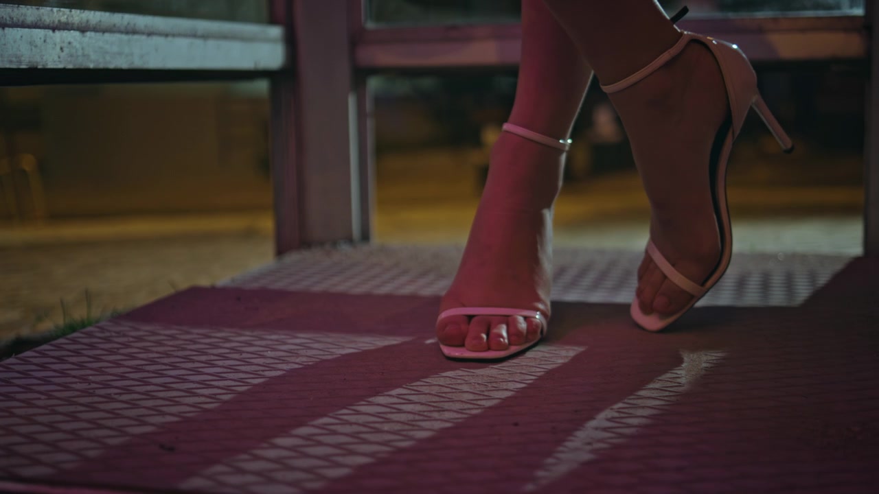 Cận cảnh đôi chân phụ nữ đi sandal cao gót trên đường phố đêm. Những bước đi thanh lịch.