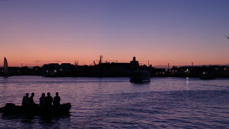 imágenes estacionarias de la hora azul de un puerto al atardecer un pequeño bote lleno de gente se desliza