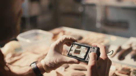 archaeologist documenting labeled artifacts with digital camera