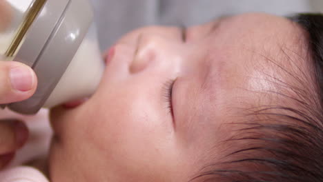 close-up of baby dozing off while drinking milk from a bottle: tender moment of infant sleepiness captured in detail