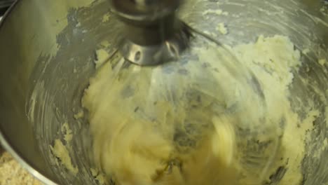 handheld shot of butter being whipped in a stand mixer