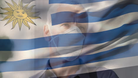 animation of flag of uruguay over man wearing face mask