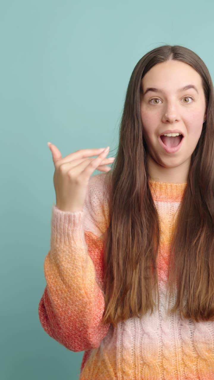Young woman expressing surprise and excitement in bright sweater