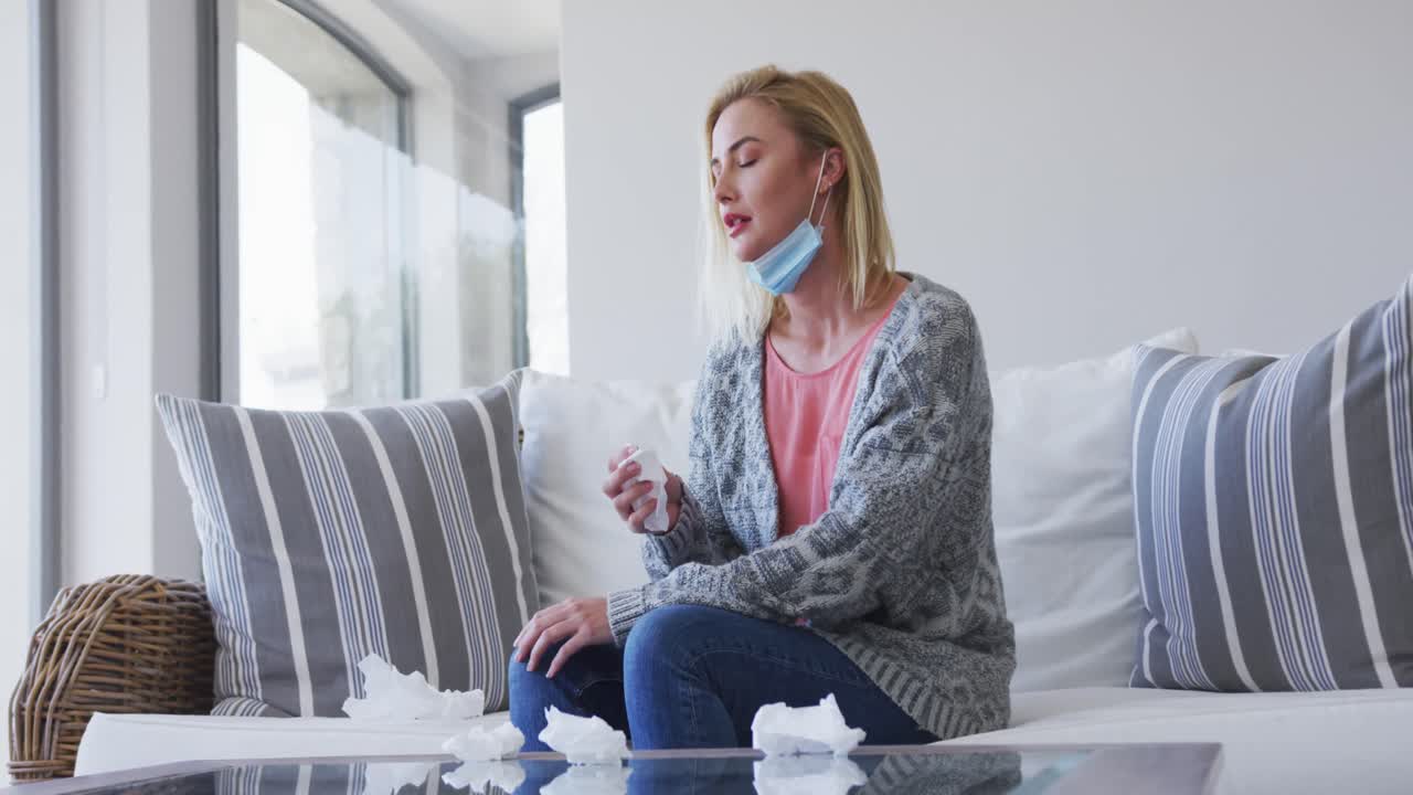 Sick woman holding tissues sitting on the couch at home