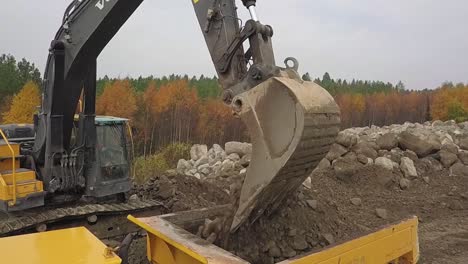 aerial, slow motion, orbit, drone shot, closely around a crawler excavators, volvo ec380el, filling up articulated truck, with soil, in pohjanmaa, finland