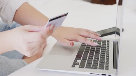 una mujer caucásica de tamaño grande usando una computadora portátil y sosteniendo una tarjeta de crédito en cámara lenta.