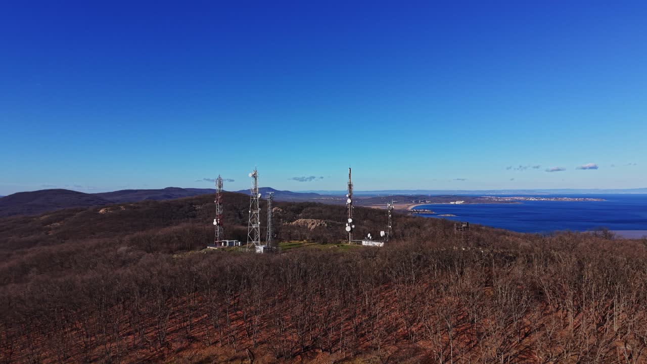 Communication towers in a mountainous area by the coast under clear sky