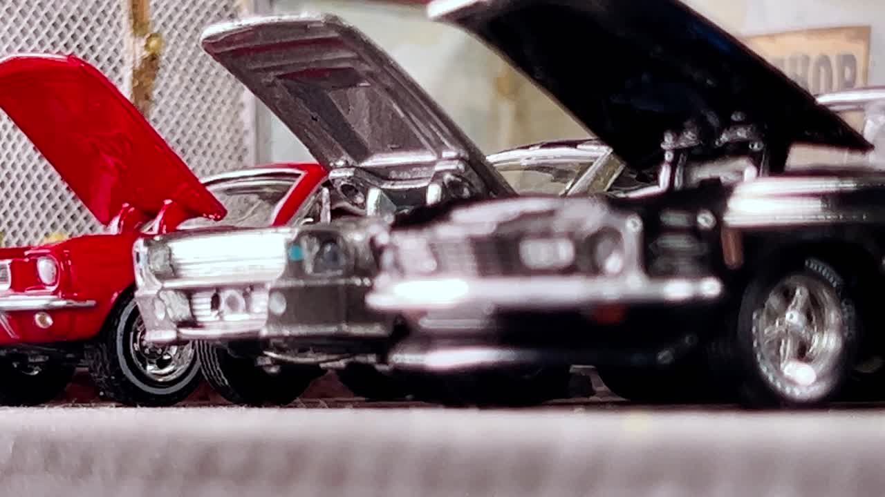 Miniature Mustang models on display with hoods open, captured from a low angle