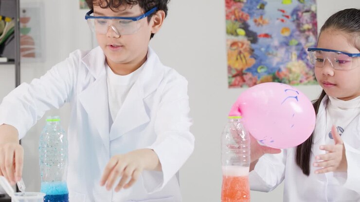 Aasialaisia lapsia laboratoriotakeissa tekee tiedekokeen puhaltaen ilmapalloja kemiallisilla reaktioilla.