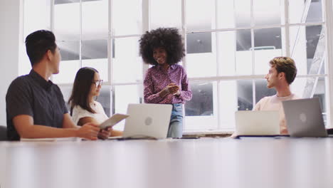 creative colleagues sitting at a table in a meeting room listening to their female boss, low angle