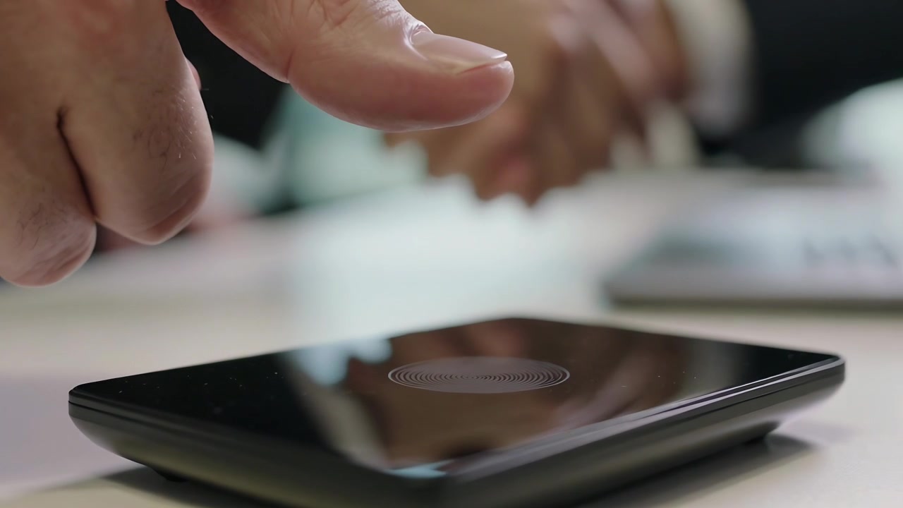 Un dito adulto si avvicina a un touchscreen nero su un tavolo, premendo per sbloccare dopo il segnale.