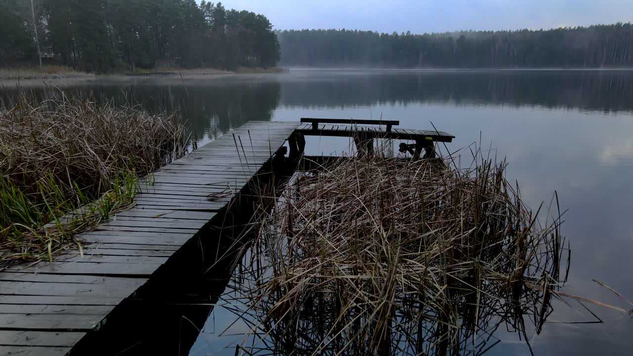 toma aérea sobre un muelle de un lago brumoso en otoño