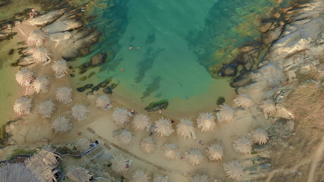 vista aérea de una hermosa playa con aguas claras de color turquesa y sombrillas de paja