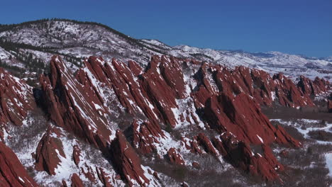 Stunning-March-winter-morning-snow-Roxborough-State-Park-Littleton-Colorado-aerial-drone-sharp-jagged-dramatic-red-rock-formations-Denver-foothills-front-range-landscape-blue-sky-backwards-motion