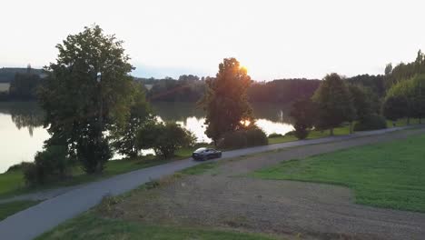 a drone shot of an electromobile driving beside the lake