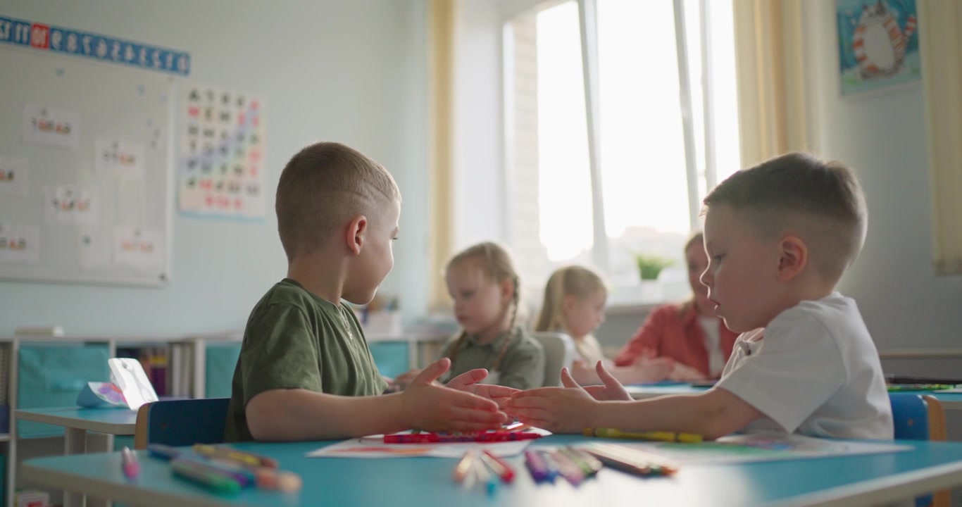 Zwei kleine Jungen spielen ein Handspiel in einem hellen Klassenzimmer