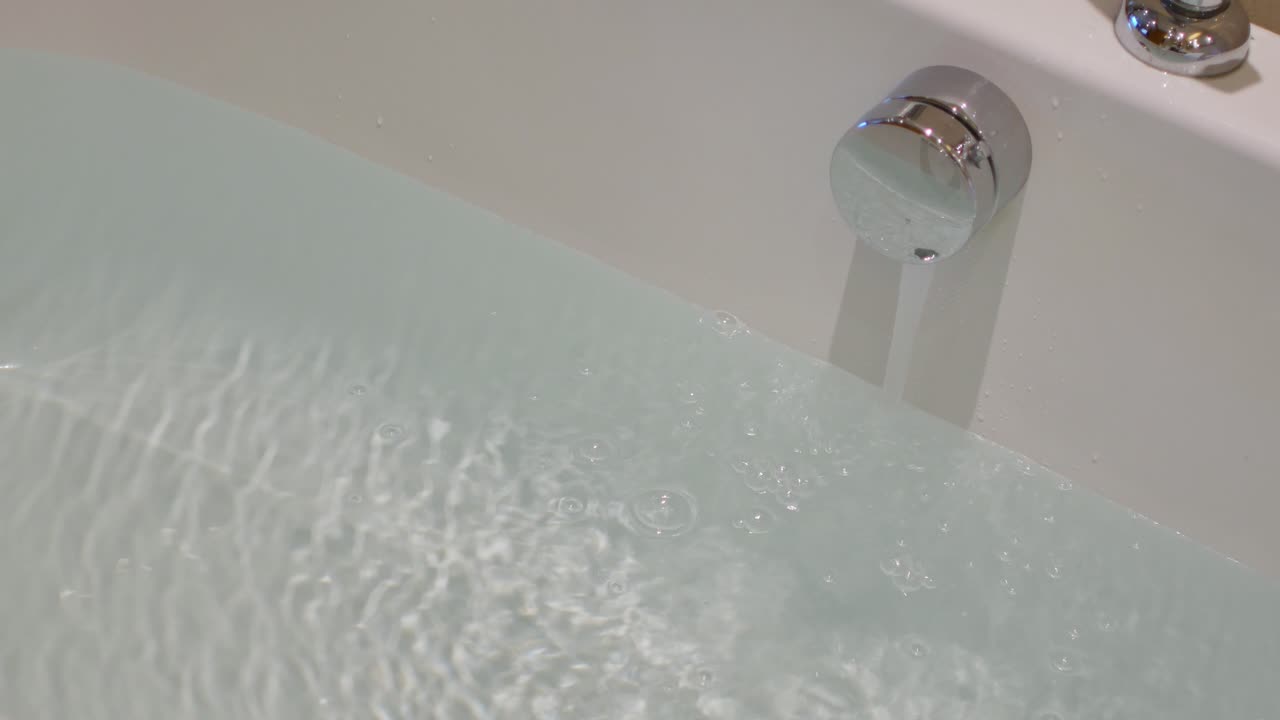 흐르는 물이 수도꼭지에서 흰색 싱크대로 흐릅니다.