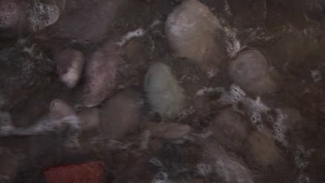 colorful pebble beach rocks covered with delicate shallow waves high angle