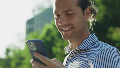 smiling man using a smartphone outdoors