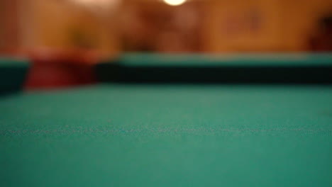 Slow-Motion-Billiards-yellow-striped-9-ball-shot-in-corner-pocket-on-pool-table-with-green-felt-and-brown-pockets-with-the-cue-ball-sliding-out-of-frame-Low-Angle-Close-Up-with-Red-Spinning-Dots