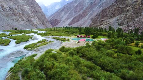 drone shot of streams of rivers with milky water in souq valley at skardu, pakistan surrounded by bushes and mountains