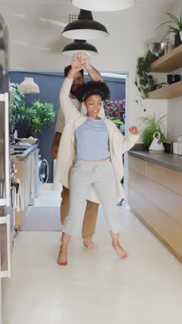 video vertical de una pareja feliz y diversa divirtiéndose bailando juntos en la cocina