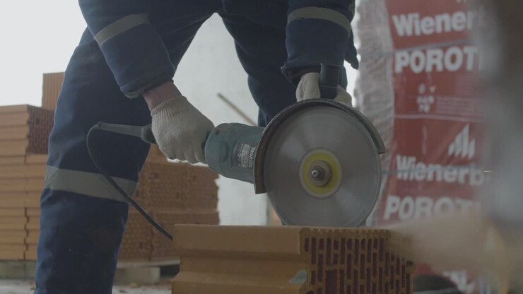 Werknemer zaagt baksteen met een cirkelzaag