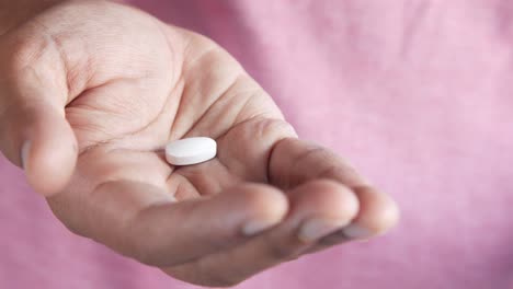 hand holding a white pill