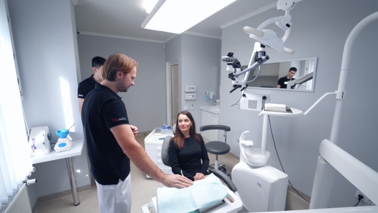 Woman at dentist's visit. Young female patient sitting into a dental chair. Beautiful woman and male stomatologist in modern dental office.