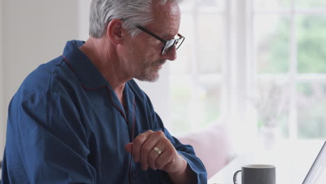 Senior-Man-At-Home-Looking-Up-Information-About-Medication-Online-Using-Laptop