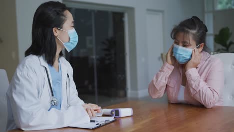 Asiatische-Krankenschwester-Trägt-Gesichtsmaske-In-Absprache-Mit-Einer-Patientin,-Die-Im-Krankenhaus-Eine-Maske-Trägt