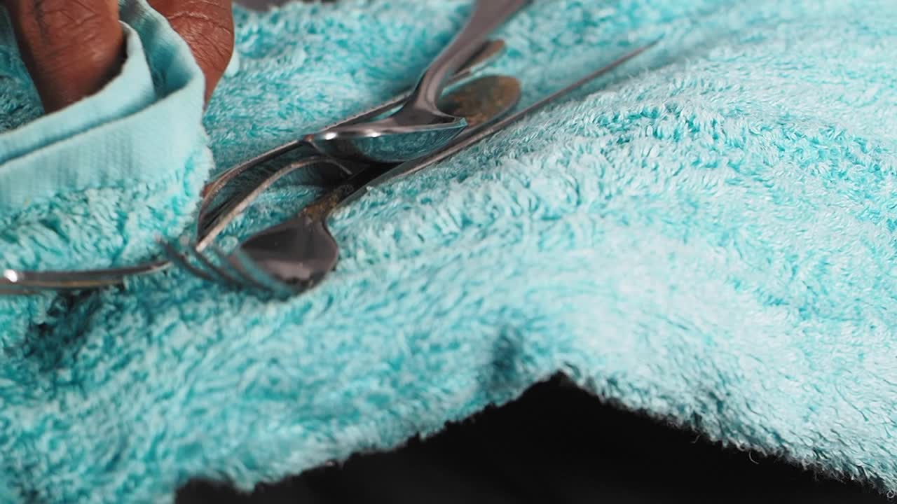 Silverware drying on a teal towel