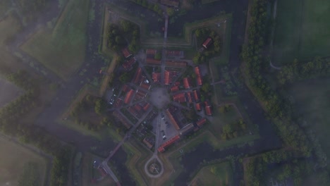 Top-down-shot-of-famous-fortress-Bourtange-in-the-Netherlands-during-foggy-morning,-aerial