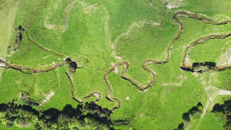 una vista de los pájaros en movimiento rápido sobre un arroyo que fluye a través de las tierras de cultivo