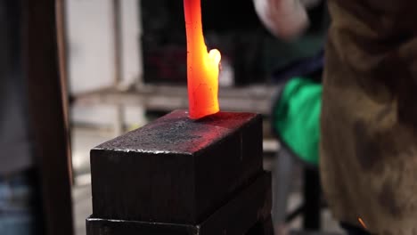 blacksmiths forging hot metal with hammer in workshop