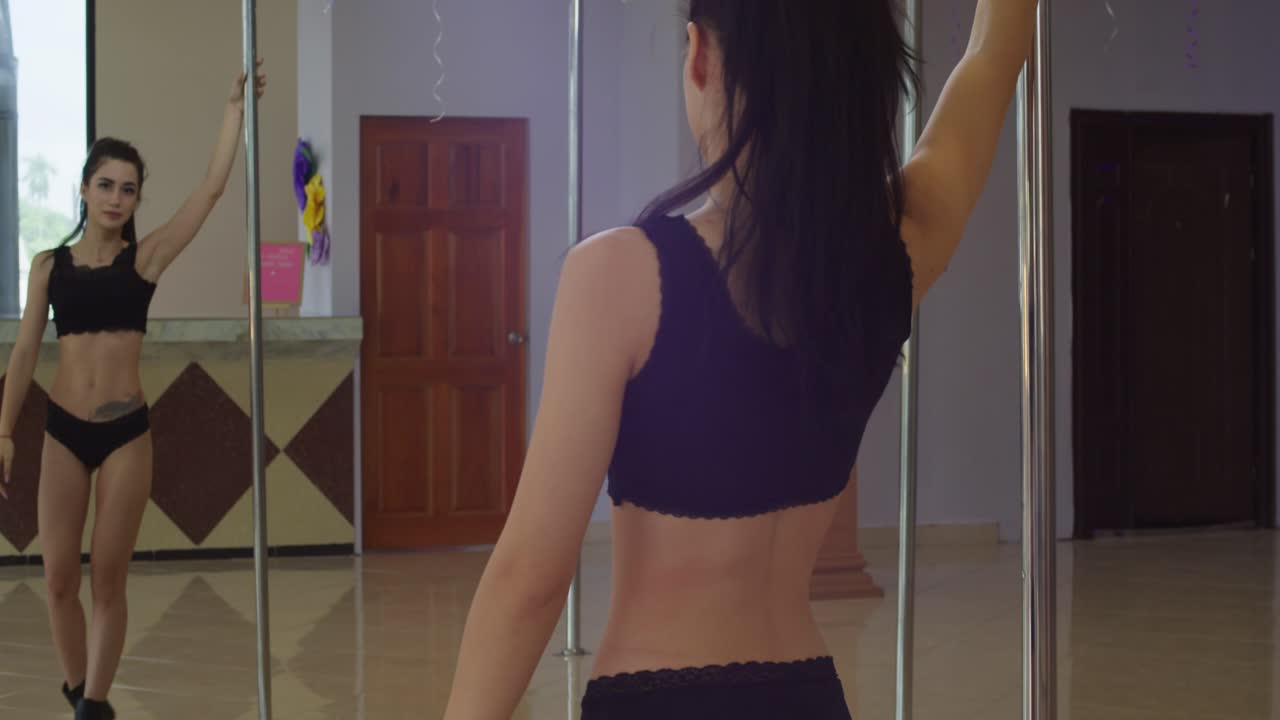 댄스 스튜디오에서 기둥 주위를 걷는 거울 속의 젊은 극 댄서의 반사