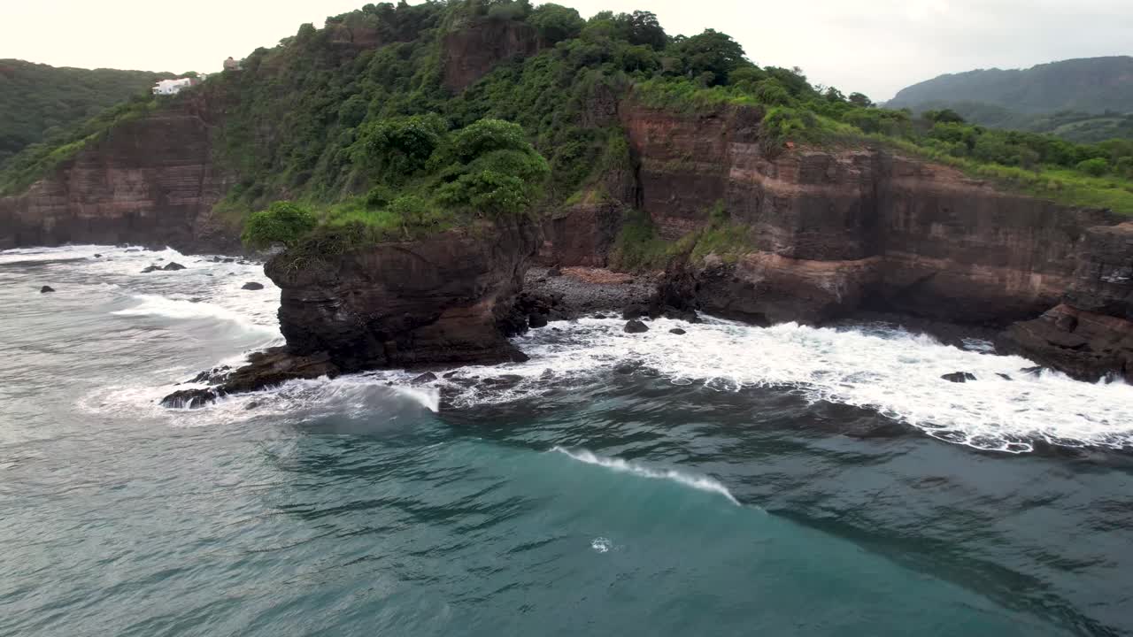 vista aérea de las olas rompiendo en las rocas en un océano azul