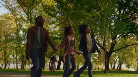 happy family walking autumn park holding hands evening. caring people together.