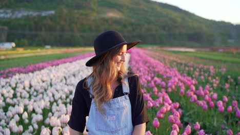 woman standing in field of tulips with large hat at sunrise in nice light in abbotsford, british columbia, canada