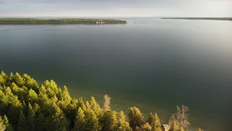 Aerial-Ascent-of-Forested-Coastline-Out-To-Lake-Huron,-Hessel,-Michigan