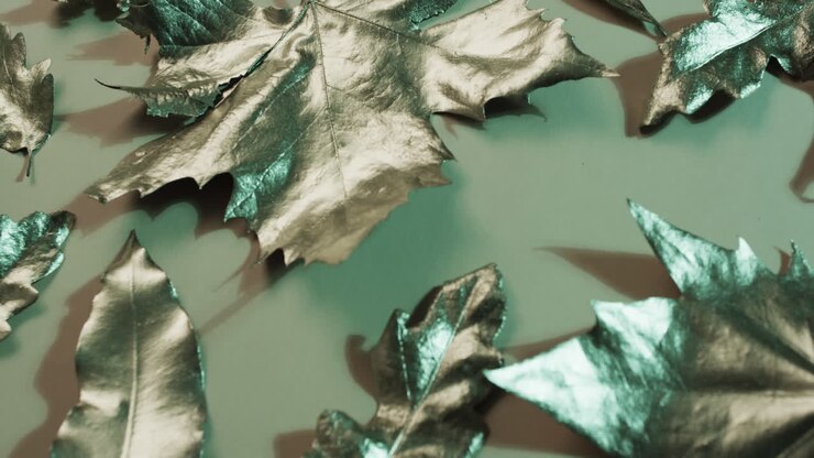 Video of halloween autumn metallic leaves with copy space on green background