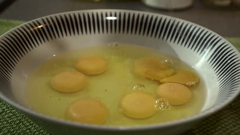 slow motion cu male chef is breaking eggs to prepare a dish