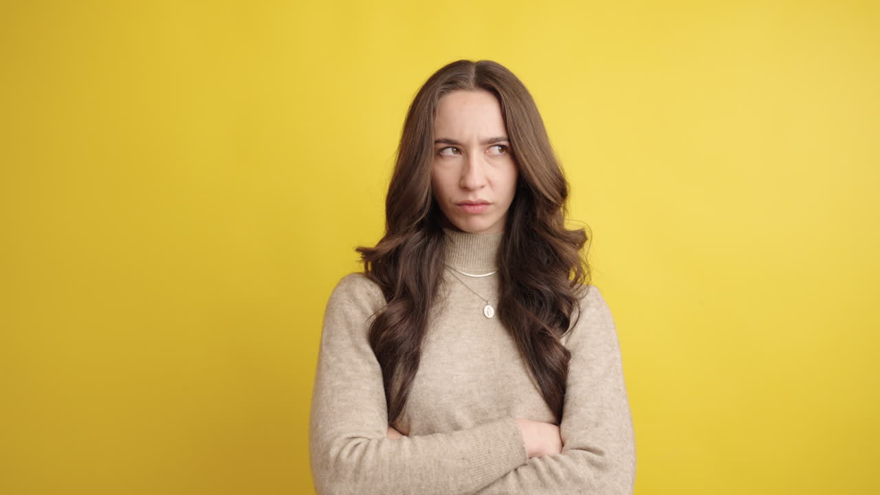 Woman showing displeasure with arms crossed on yellow background
